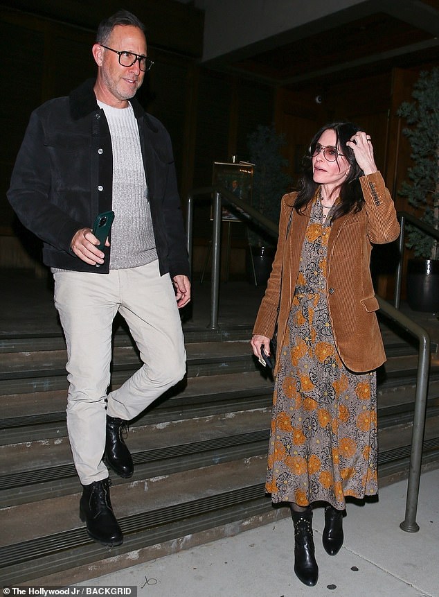 Выпускница «Друзей» была одета в платье миди с цветочным принтом и юбку А-силуэта в оттенках черного, серого и мандаринового цвета.  Звезда «Города хищниц» согрелась в ярко-оранжевом вельветовом пиджаке с черными пуговицами и карманами.