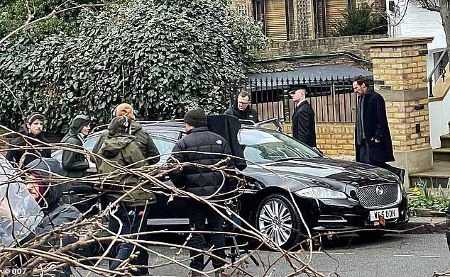 На другом снимке можно увидеть, как съемочная группа и актеры слонялись вокруг черной машины, готовясь начать съемки.