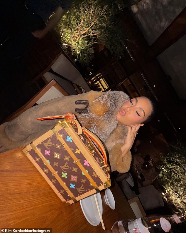 Ким обхватила ее губами за столом с ее дорогой сумкой Louis Vuitton Box, которая заметно отдыхала на переднем плане